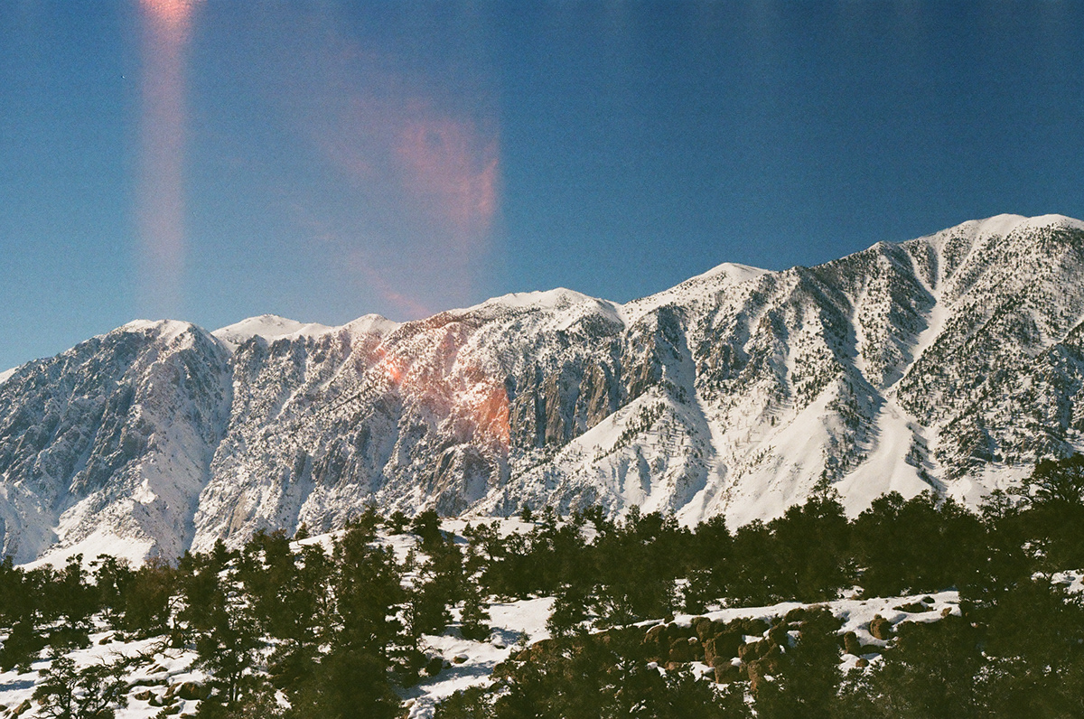 Snow-covered mountain range under a deep blue sky with a film light leak